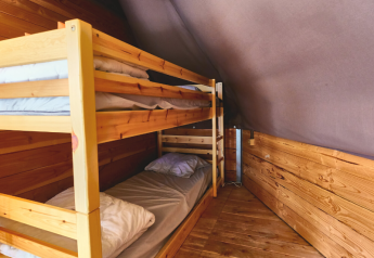Innenansicht des Tipi Tent bei Ludo Camping in Frankreich mit Holzboden und Etagenbetten.