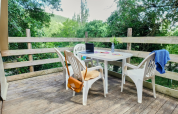 Buitenterras met witte plastic stoelen bij Tipi Tent op Ludo Camping in Frankrijk, omringd door groen.