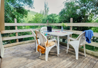 Buitenterras met witte stoelen bij Tipi Tent op Ludo Camping in Frankrijk, omgeven door natuur.