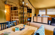 Binnenaanzicht van Lodge «COSY» safaritent bij Ludo Camping in Frankrijk, met eettafel en keuken.