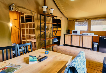 Interno della tenda safari Lodge «COSY» al Ludo Camping in Francia con tavolo da pranzo e cucina.