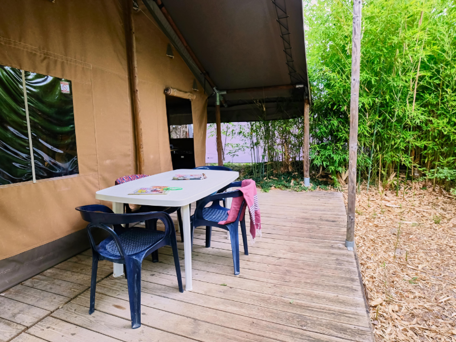 Buitenterras met tafel en stoelen bij Lodge «COSY» safaritent op Ludo Camping in Frankrijk.