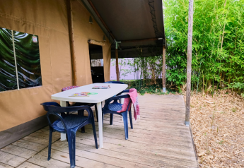 Überdachte Terrasse mit Tisch und Stühlen am Lodge „COSY“ Safarizelt im Ludo Camping, Frankreich.