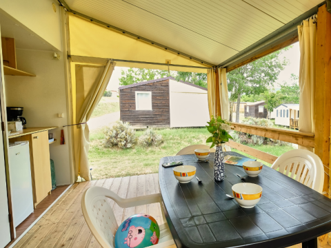 Tenda safari 'Bungalowtent' al campeggio Ludo in Francia con tavolo apparecchiato sulla veranda.