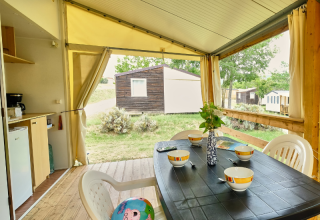 Tienda safari 'Bungalowtent' en Ludo Camping, Francia, con mesa puesta en terraza de madera.