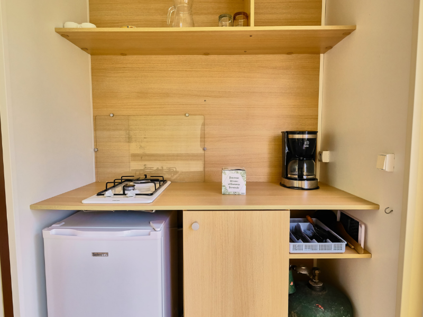 Kleine kitchenette in een Bungalowtent op Ludo Camping met gasfornuis, koffiezetapparaat en koelkast.