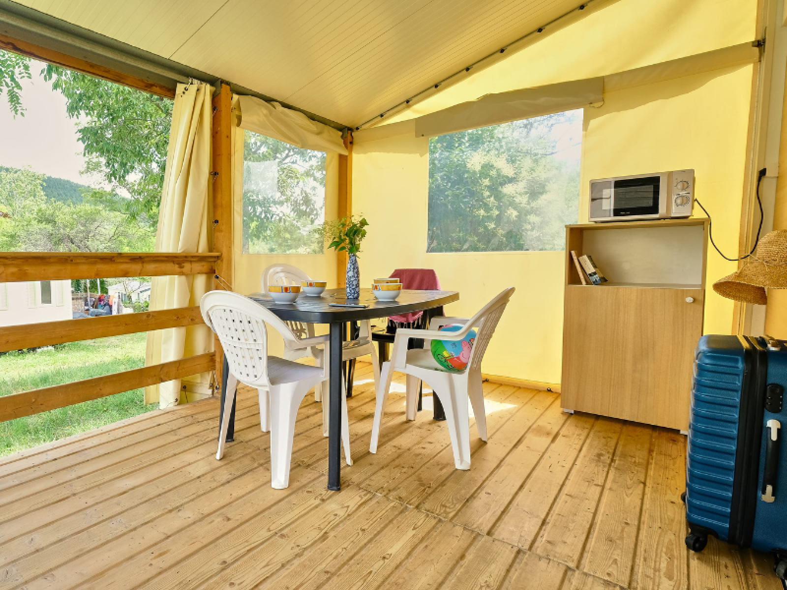 Binnenkant van safari bungalowtent bij Ludo Camping in Frankrijk met tafel, stoelen en kastje.