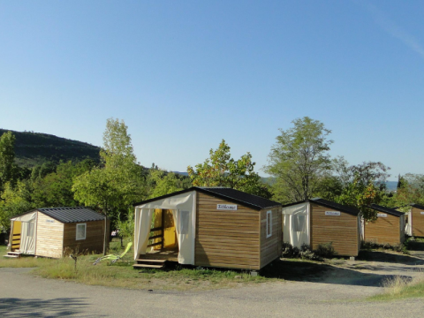 Tende bungalow al campeggio Ludo in Francia, immerse nella natura con alberi e cielo azzurro limpido.