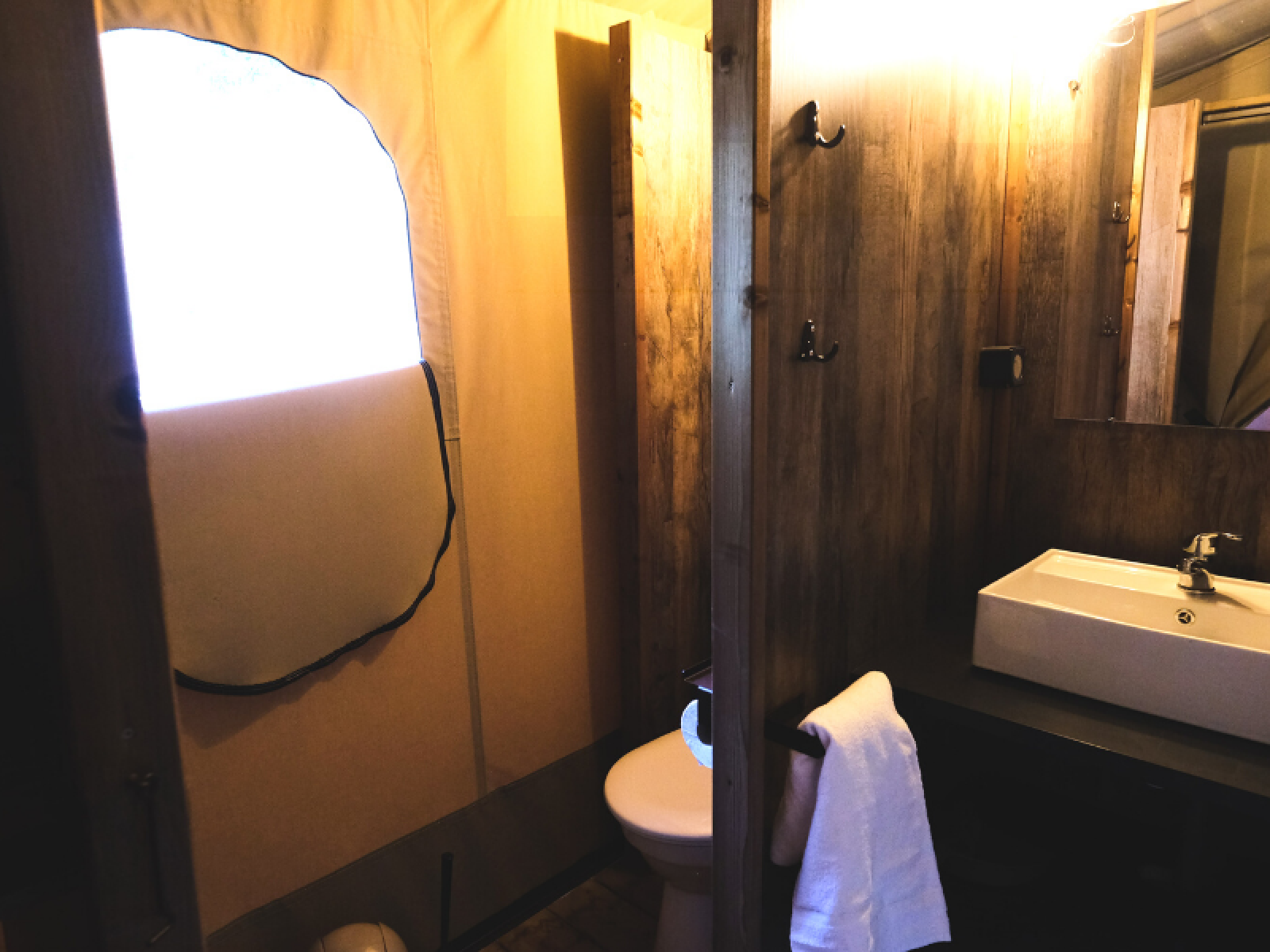 Badkamer in Lodge PREMIUM safaritent bij Ludo Camping, Frankrijk, met wastafel, spiegel en toilet.