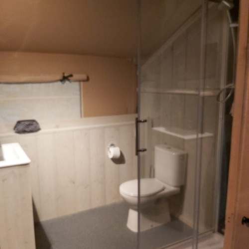 Bathroom inside a safari tent at Ranger Lodge, Petite Suisse, Belgium, with toilet and corner shower.