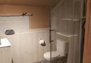 Bathroom inside a safari tent at Ranger Lodge, Petite Suisse, Belgium, with toilet and corner shower.