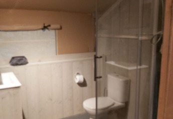 Baño en tienda safari en Ranger Lodge, Petite Suisse, Bélgica, con inodoro y ducha en la esquina.