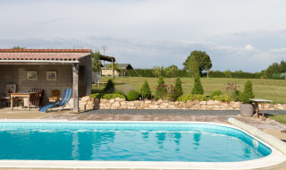 Udendørs swimmingpool med terrasse og have ved La Maison Bornat feriepark i Bourgogne-Franche-Comté, Frankrig.