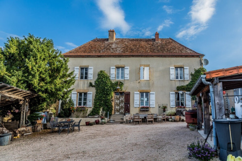 Charmantes, historisches Ferienhaus mit Efeu und weißen Fensterläden in Bourgogne-Franche-Comté, Frankreich.