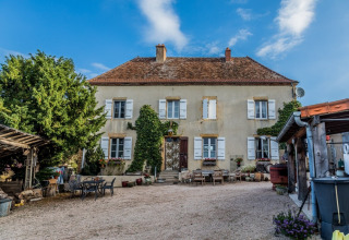 Et charmerende, gammeldags fransk landhus med klatreplanter og udendørs møbler i Bourgogne-Franche-Comté.
