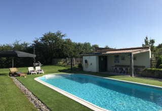 Außenpool bei La Maison Bornat in Bourgogne-Franche-Comté, Frankreich, mit Liegestühlen und Gartenfläche.