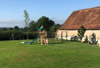Aire de jeux à La Maison Bornat avec balançoires, toboggan et jardin en Bourgogne-Franche-Comté, France.