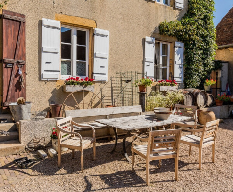 Charmerende gårdhave ved La Maison Bornat feriested i Bourgogne-Franche-Comté med rustikke møbler.