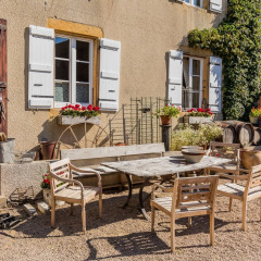 Sfeervolle binnenplaats bij La Maison Bornat vakantiepark in Bourgogne-Franche-Comté met rustiek meubilair.