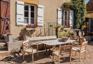 Charmerende gårdhave ved La Maison Bornat feriested i Bourgogne-Franche-Comté med rustikke møbler.