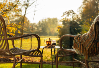 Twee rotan stoelen en een tafeltje met thee op het terras bij Wellness Duynzicht, Sandberghe, Nederland.