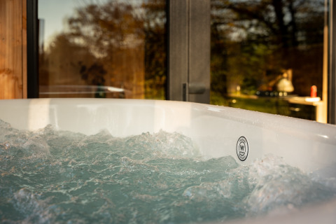 Outdoor hot tub at Wellness Duynzicht lodge at Sandberghe in the Netherlands with scenic nature view.