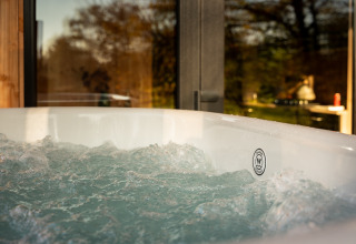 Outdoor hot tub at Wellness Duynzicht lodge at Sandberghe in the Netherlands with scenic nature view.