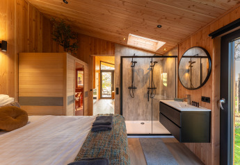 Modern lodge-interieur met hout, kingsize bed, douche en sauna bij Wellness Duynzicht, Sandberghe, Nederland.