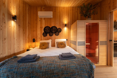 Bedroom at Wellness Duynzicht lodge with a sauna, wooden walls, and double bed at Sandberghe in the Netherlands.