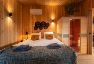 Bedroom at Wellness Duynzicht lodge with a sauna, wooden walls, and double bed at Sandberghe in the Netherlands.