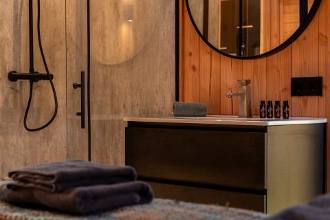 Modern badkamerinterieur bij Wellness Duynzicht, Sandberghe, Nederland, met handdoeken en verzorgingsproducten.
