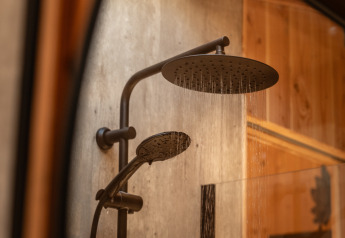 Douchekop in Wellness Duynzicht, Sandberghe, Nederland. Modern ontwerp met houten muur op de achtergrond.