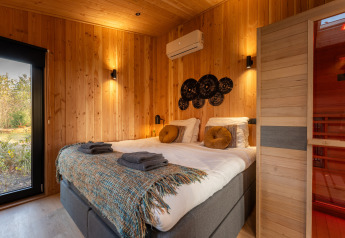 Gezellige slaapkamer in Wellness Duynzicht, Sandberghe, Nederland, met houten muren en een sauna.