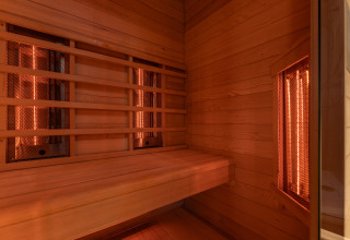 Innenansicht einer Infrarotsauna mit Holzbänken im Wellness Duynzicht, Sandberghe, Niederlande, warme Atmosphäre.