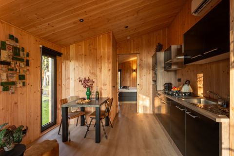 Modernes Lodge Wellness Duynzicht bei Sandberghe, Niederlande, mit Holzinterieur und offener Küche.