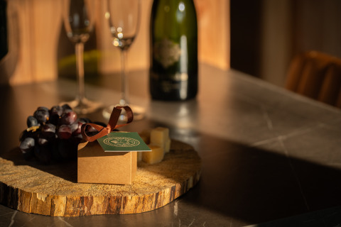 Gift box with ribbon, grapes, cheese, wine bottle, and glasses on a table at Wellness Duynzicht, Sandberghe.
