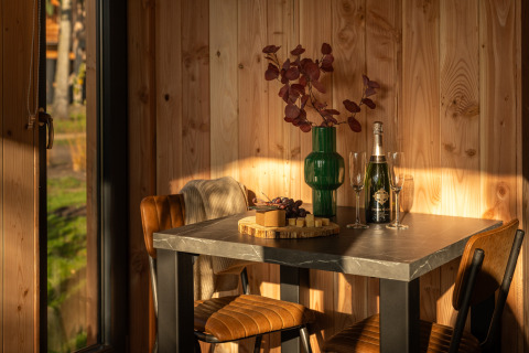 Sonniger Tisch im Wellness Duynzicht, Sandberghe, Niederlande, mit Wein, Gläsern, Käse und Vase.