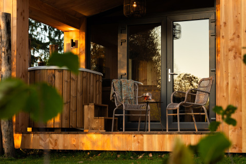 Outdoor terrace at Wellness Duynzicht lodge in Sandberghe, Netherlands, with seating and a wooden hot tub.