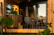 Outdoor terrace at Wellness Duynzicht lodge in Sandberghe, Netherlands, with seating and a wooden hot tub.