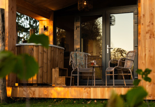 Outdoor terrace at Wellness Duynzicht lodge in Sandberghe, Netherlands, with seating and a wooden hot tub.