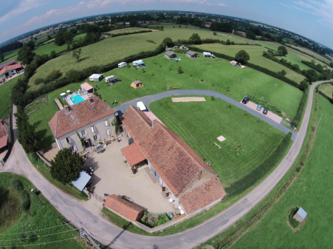 Aerial view of La Maison Bornat holiday park in Bourgogne-Franche-Comté, France, showing fields and a pool.