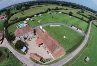 Vista aérea del parque vacacional La Maison Bornat en Bourgogne-Franche-Comté, Francia, con campos y piscina.