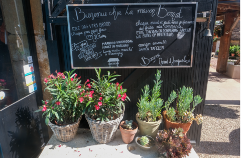 Panneau d'entrée et pots de fleurs à La Maison Bornat, parc de vacances en Bourgogne-Franche-Comté, France.