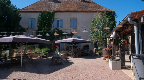 Buitenterras bij La Maison Bornat vakantiepark in Bourgogne-Franche-Comté, Frankrijk, met parasols en zitplaatsen.