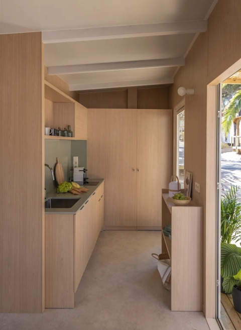 Moderne lichte houten keuken in tiny house bij Wecamp Cala Montgó, Spanje, met zicht naar buiten.