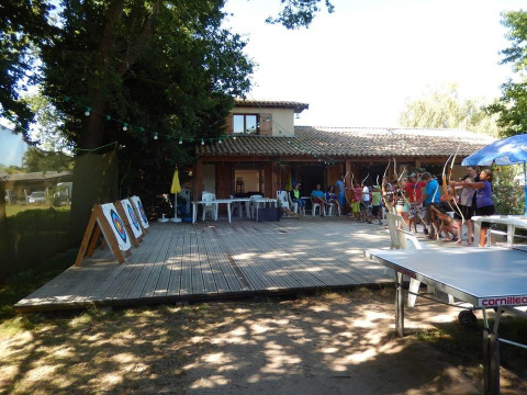 Campers practice archery on a wooden deck at Campsite Les Franquettes in Nouvelle-Aquitaine, France.