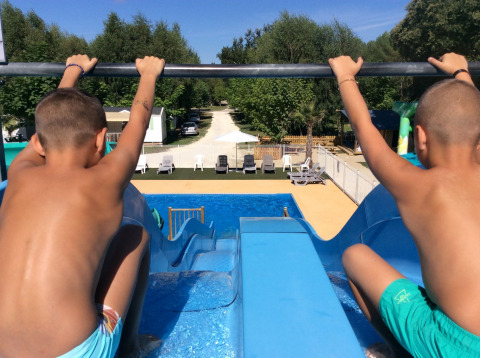 Due bambini pronti a scendere dallo scivolo d'acqua nella piscina del campeggio Les Franquettes in Francia.