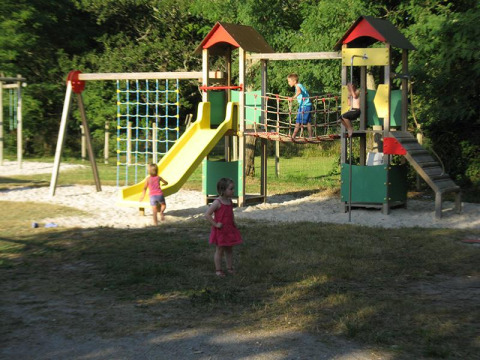 Bambini giocano su un parco giochi con scivolo e ponte al campeggio Les Franquettes, Francia.