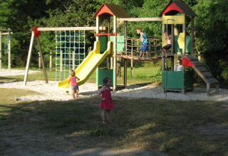 Children playing on a playground with slide and climbing frame at Campsite Les Franquettes, France.