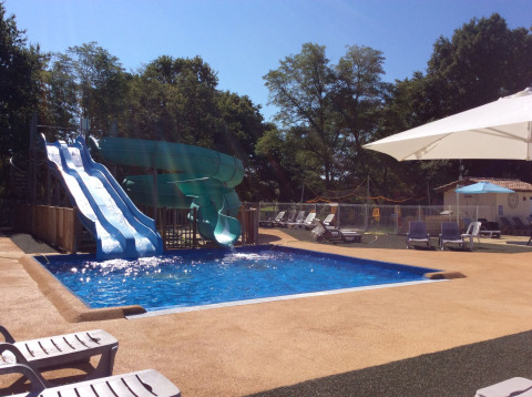Outdoor swimming pool with waterslides and sun loungers at Campsite Les Franquettes in Nouvelle-Aquitaine, France.